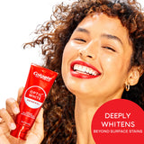 A woman smiling holding a tube of Colgate Optic White Renewal High Impact White Toothpaste. In text: Deeply whitens beyond surface stains.