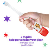 A kid's hand holding a Colgate Kids Advanced Cavity Fighter Battery Toothbrush. In text: 2 modes help personalize your clean - everyday clean and gentle clean.