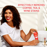 A woman smiling holding a tube of Colgate Optic White Renewal High Impact White Toothpaste. In text: Effectively removes coffee, tea, & wine stains.