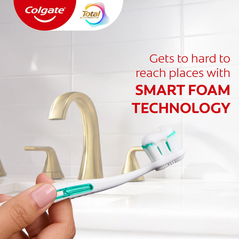 A hand holding a toothbrush with Colgate Total Plaque Pro Release Toothpaste. In text: Gets to hard to reach places with Smart Foam technology.