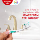 A hand holding a toothbrush with Colgate Total Plaque Pro Release Toothpaste. In text: Gets to hard to reach places with Smart Foam technology.
