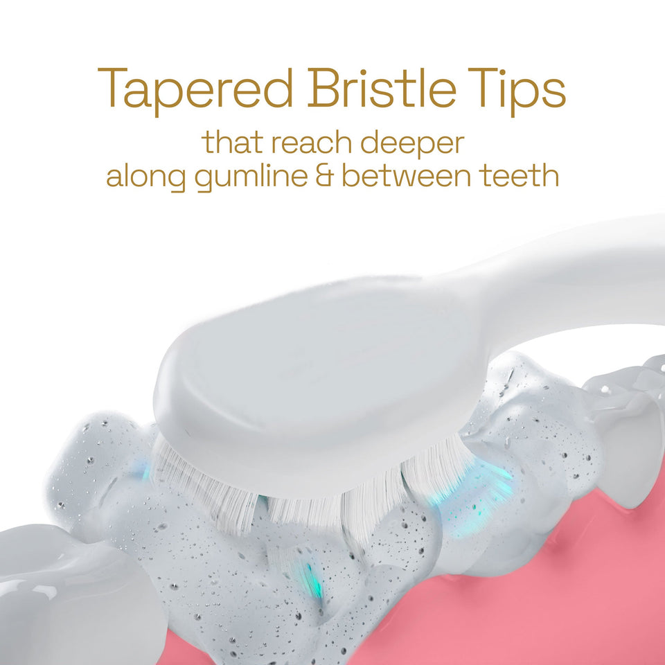 Teeth being brushed with a White Colgate Total Battery Powered Toothbrush. In text: Tapered bristle tips that reach deeper along gumline & between teeth.