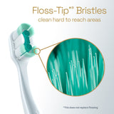 A Colgate Total Active Prevention Foaming Clean Soft Toothbrush with a close-up of the bristles. In text: Floss-Tip* Bristles clean hard to reach areas. *This does not replace flossing.