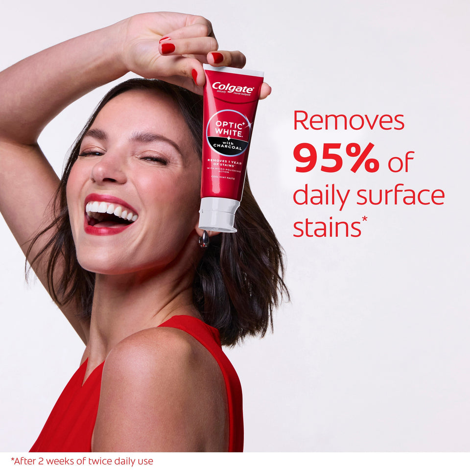 A woman smiling while holding a tube of Colgate Optic White with Charcoal Teeth Whitening Toothpaste. In text: Removed 95% of daily surface stains*. After 2 weeks of twice daily use. 